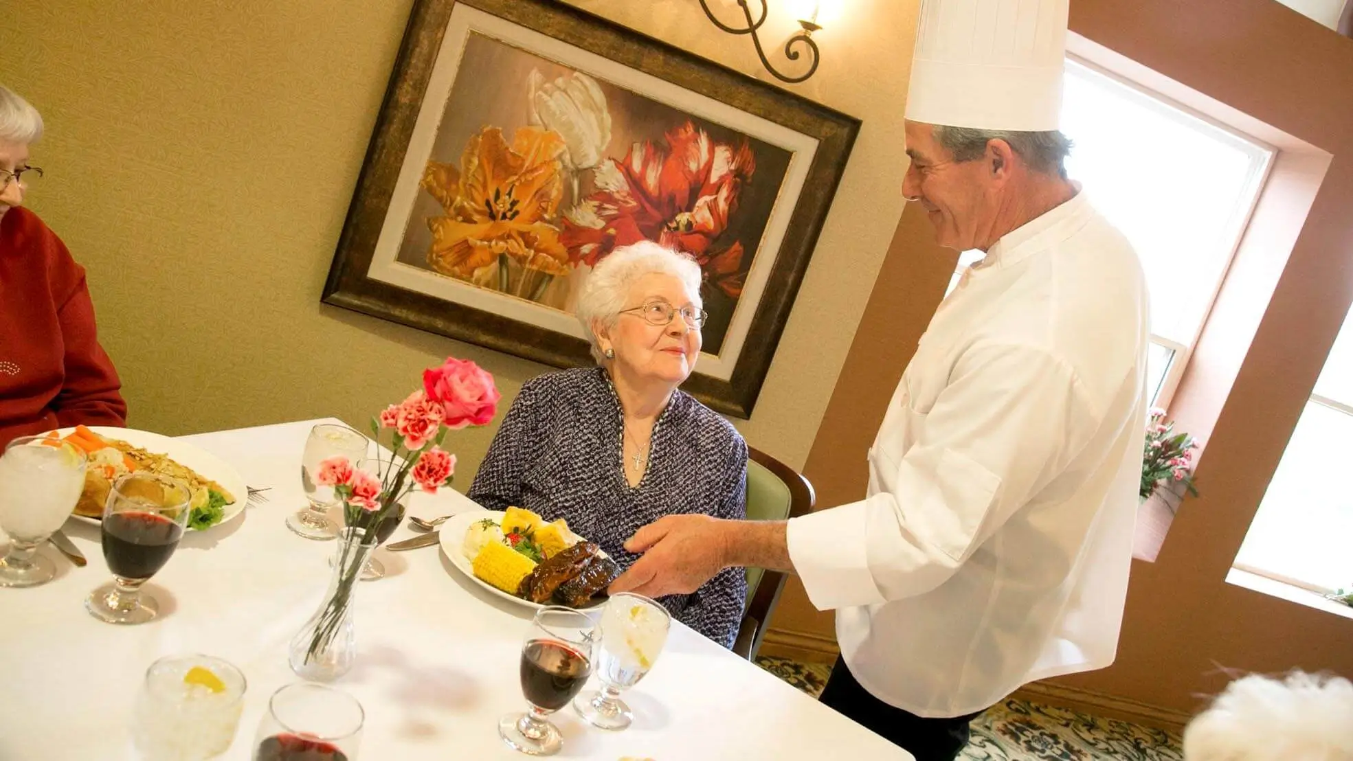 Senior resident receiving a meal from a chef.