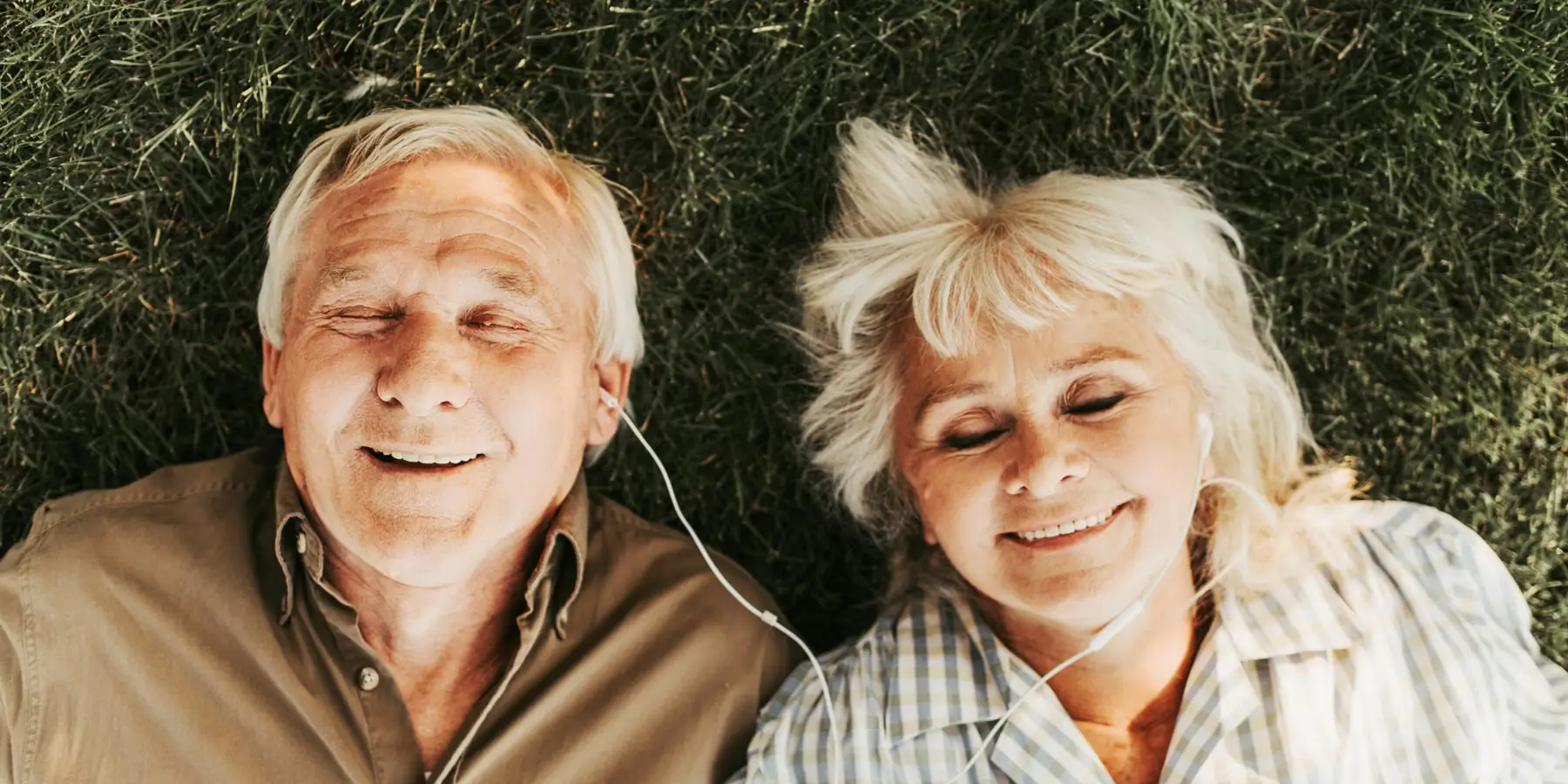 Senior couple laying in the grass listening the music.