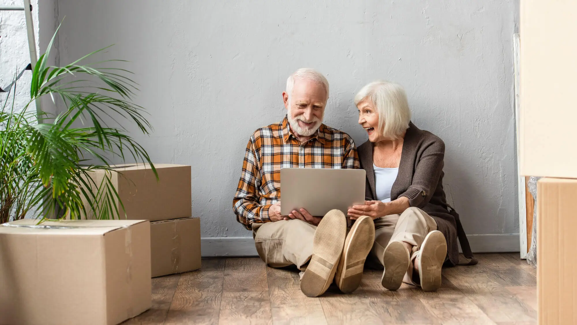 happy senior couple using laptop sitting on floor, moving concept