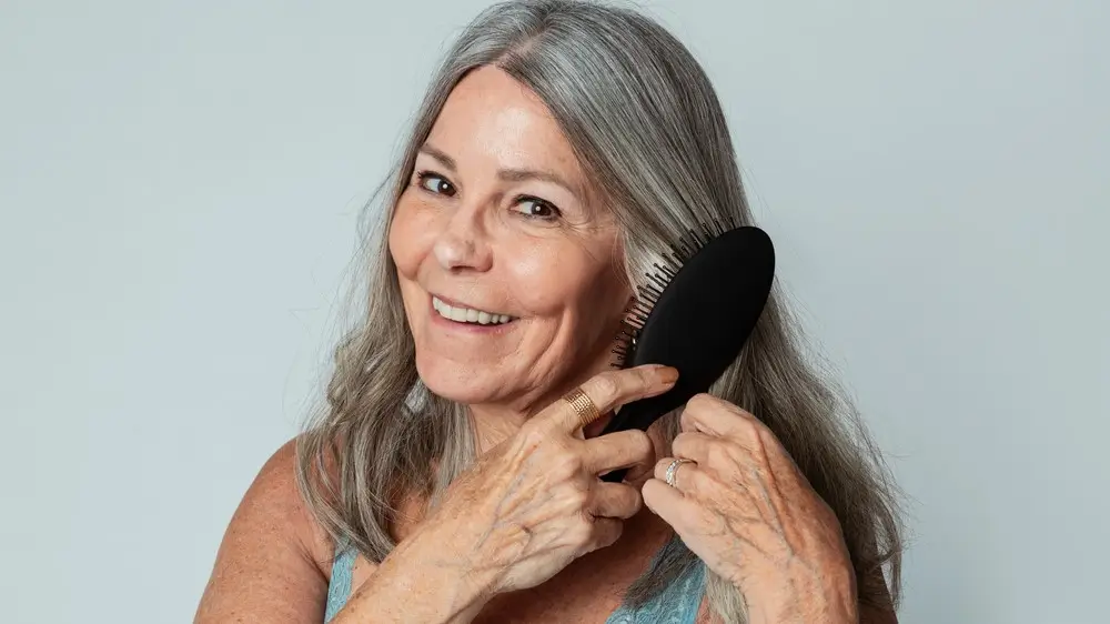 Cheeful senior woman brushing her hair