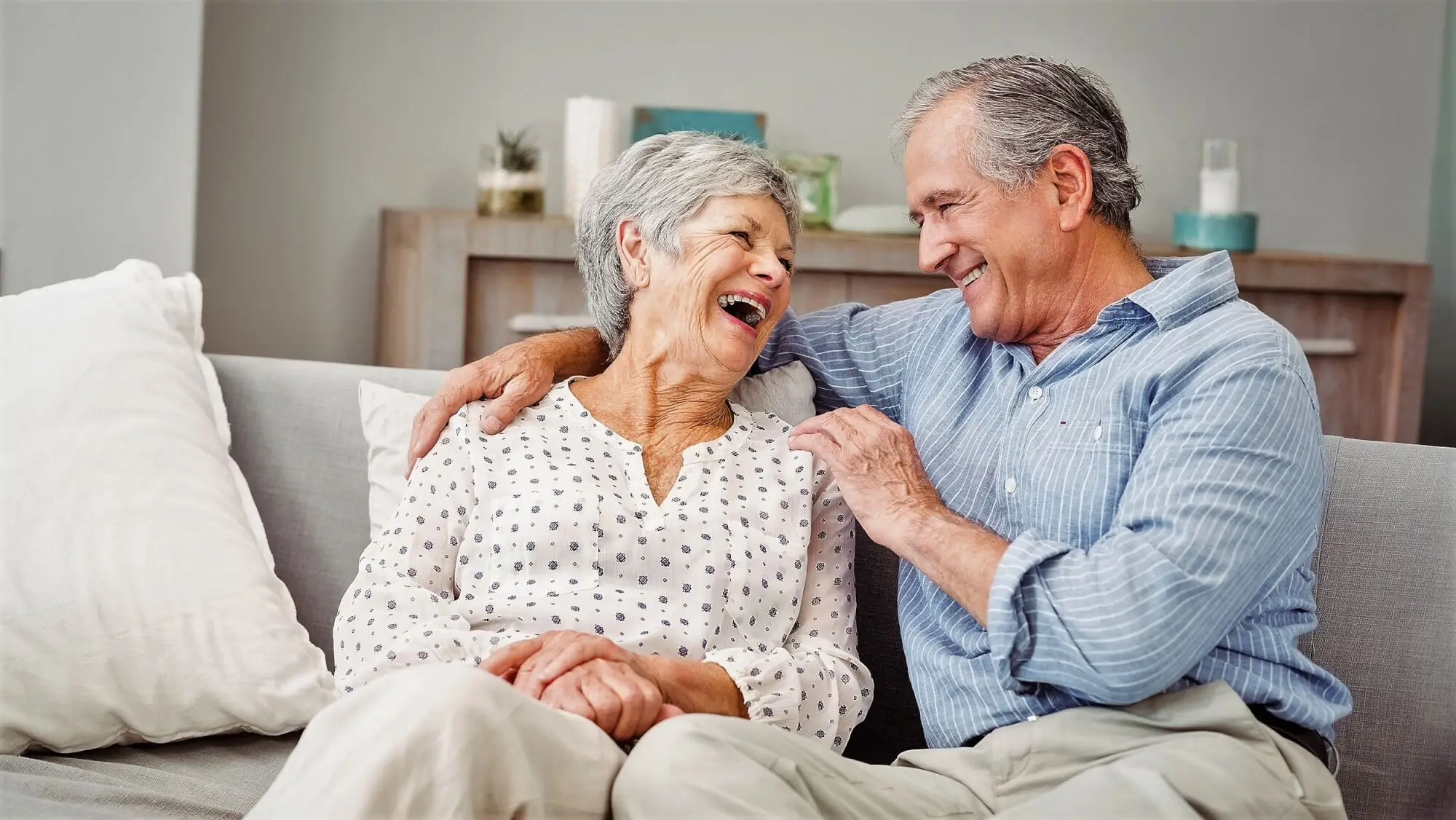 Husband and wife have a laugh together on their couch.