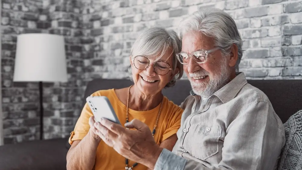 Elderly grandfather and grandmother spend time having fun using smartphone apps, middle-aged wife enjoy online entertainments, taking selfie with old husband, older generation and modern tech concept