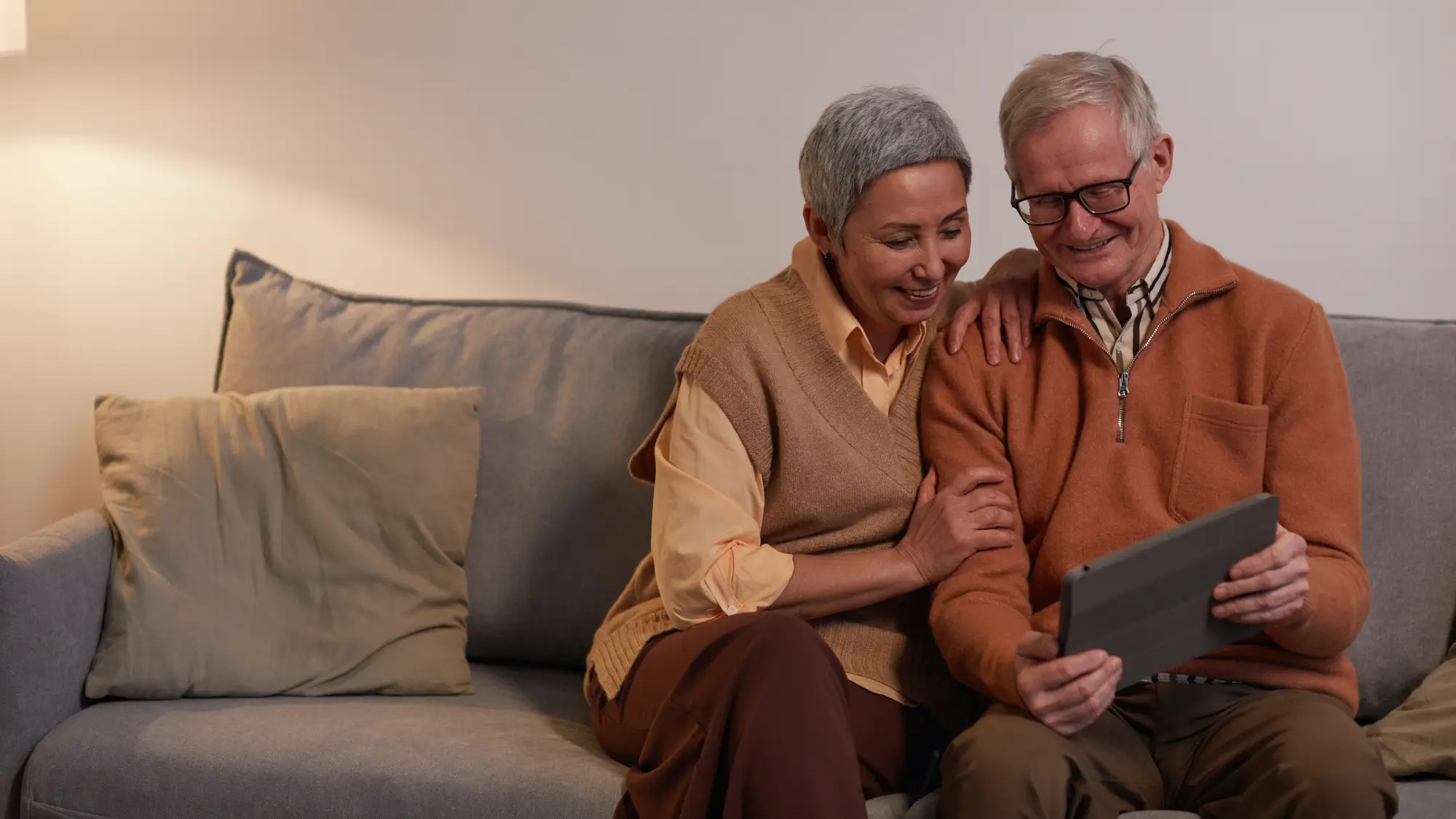 Man and Woman Sitting on Sofa While Looking at a Tablet Computer