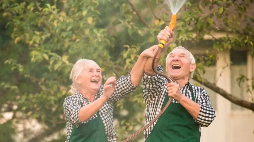 People having fun in garden. Woman and man, water hose.