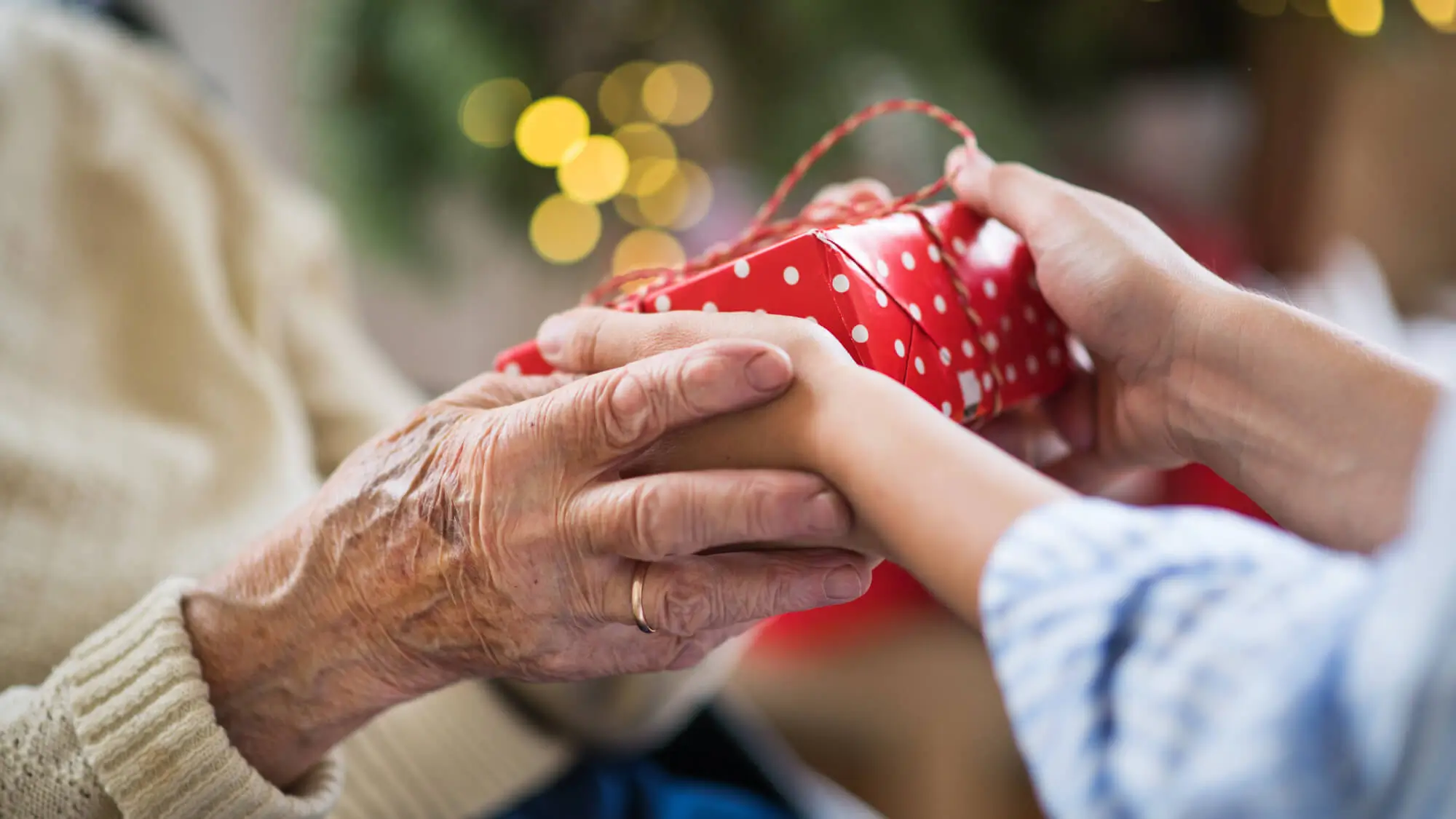 Close-up of hands of senior and young woman holding a present at Christmas.