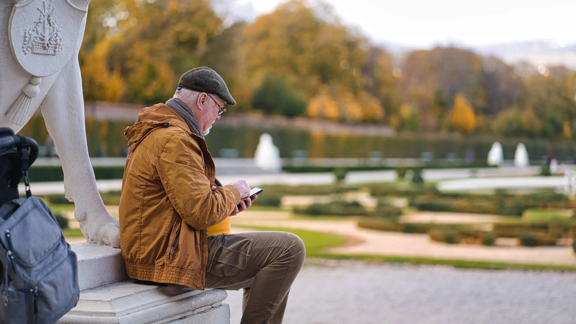 An old man sits on the stairs and surfs social networks