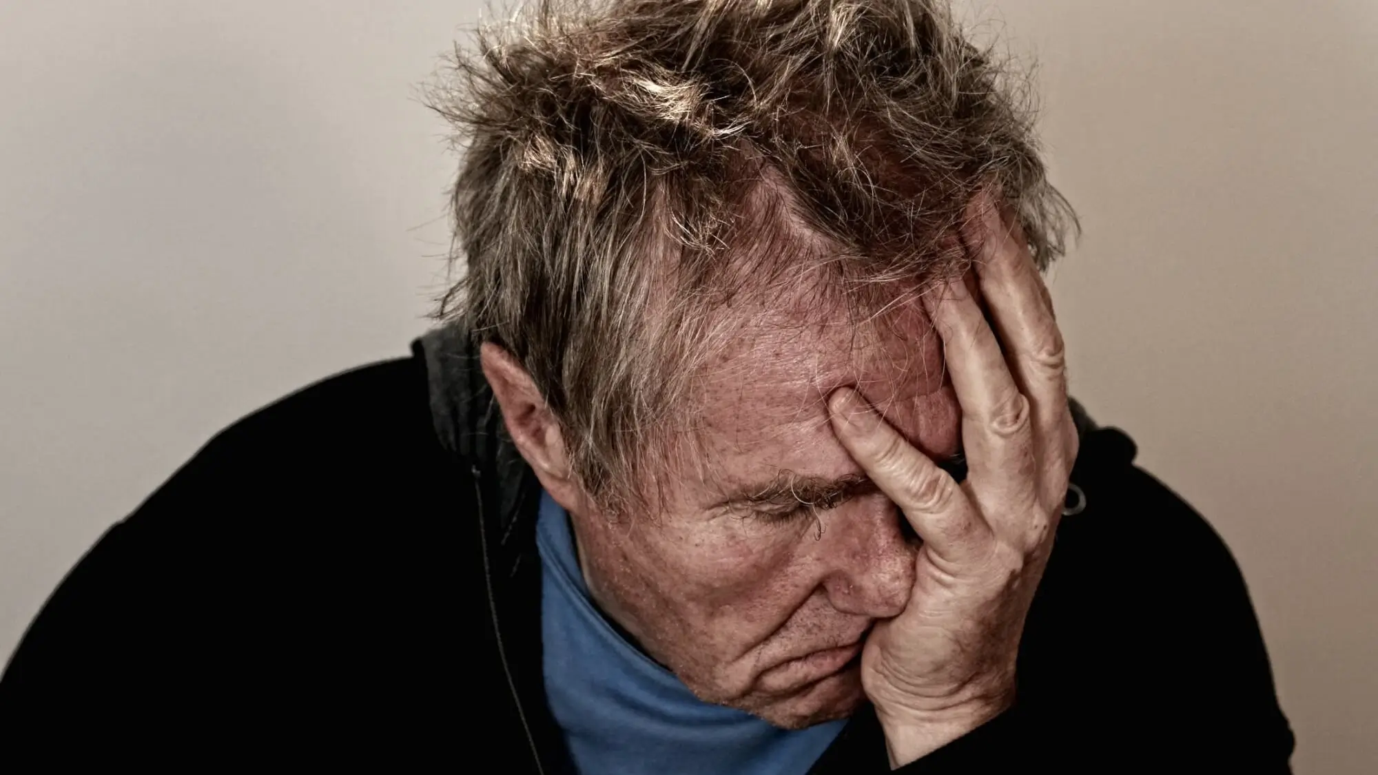 Elder man holding his hand to his head