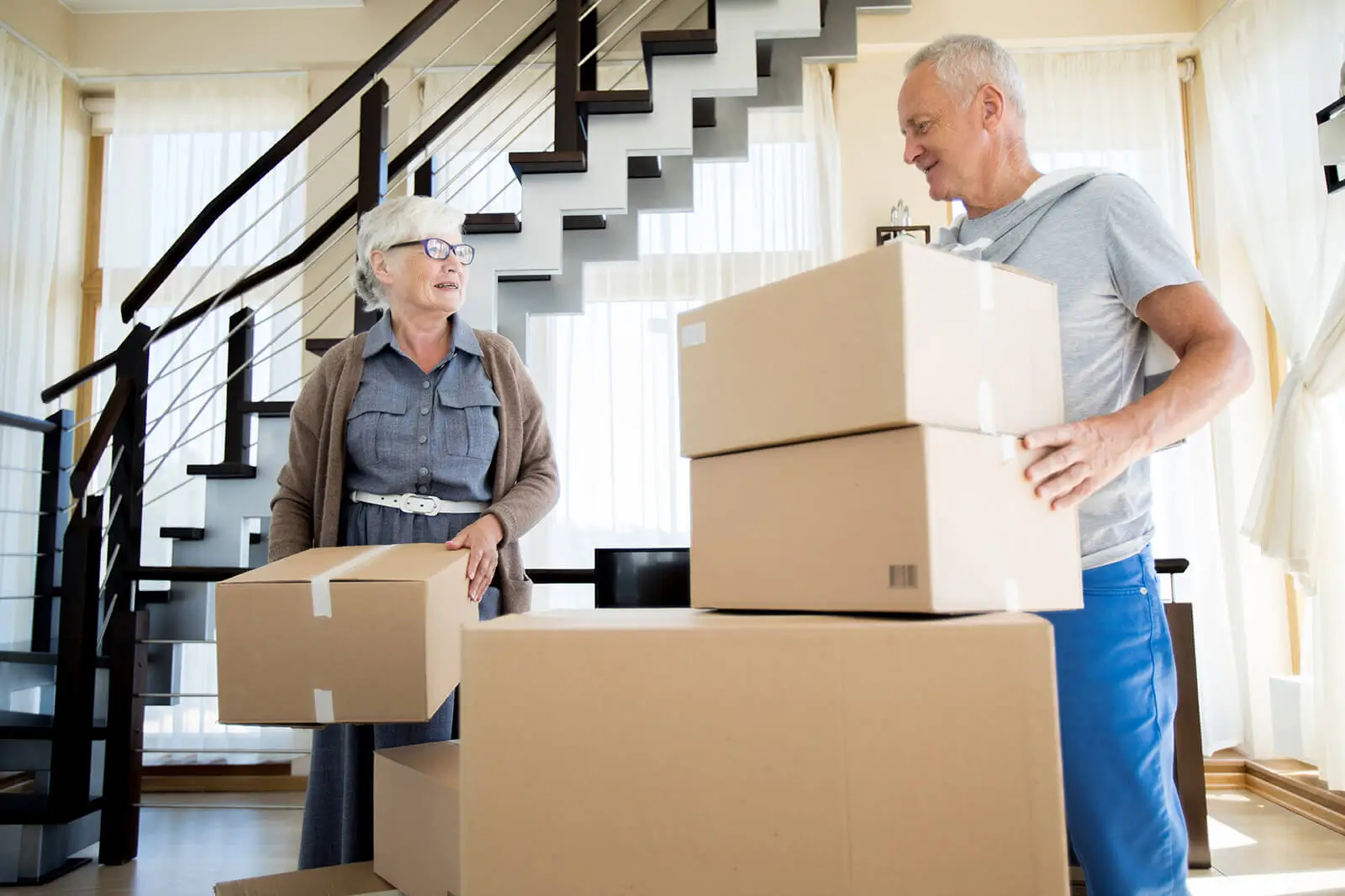 Senior couple moving into a new house carrying in their boxes.