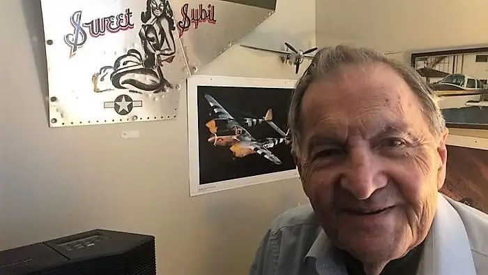 World War II veteran and retired doctor Paul Stobnicke, 96, in his apartment at Towne Center Retirement Community in Fayetteville. Behind him is a replica of the decoration from the nose cone of his P-38 fighter that honors his late wife, Sybil.