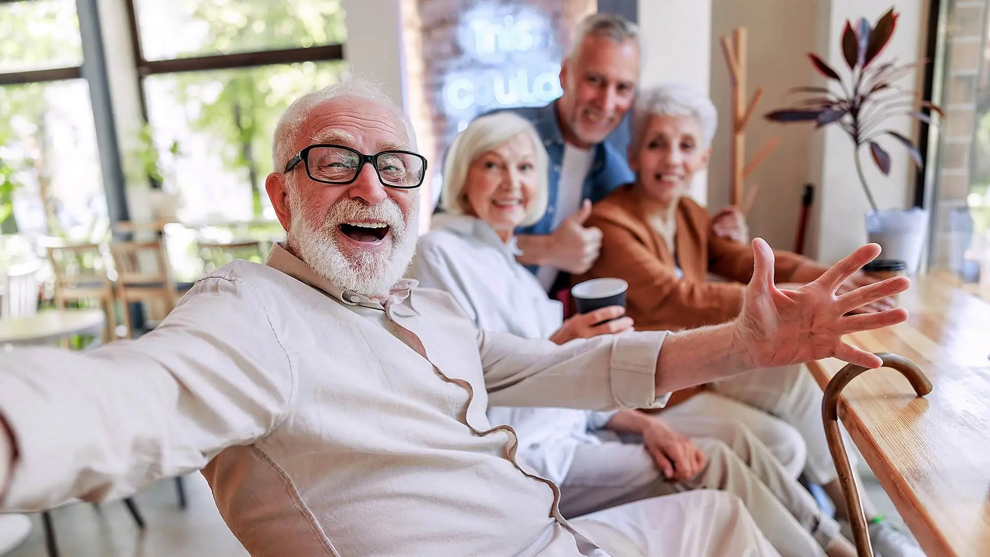 Excited senior resident hanging out with 3 friends at coffee bar.