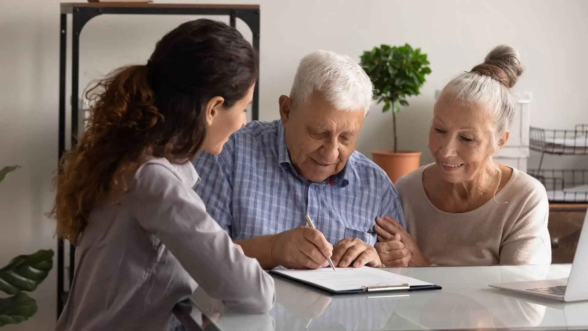 Happy senior man and woman clients sign deal sell house together. Excited elderly couple spouses put signature on document.