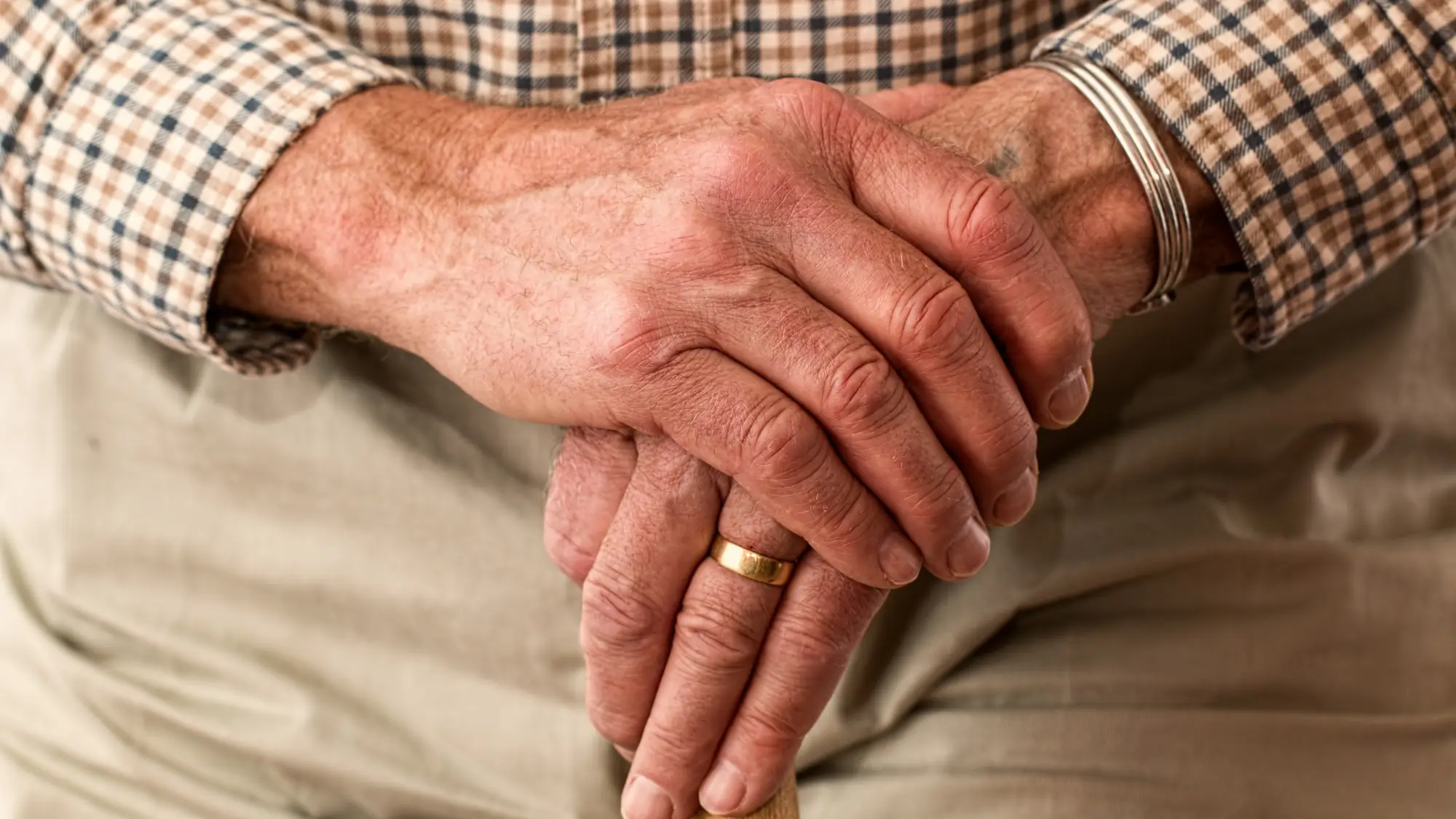 Elderly hands holding cane