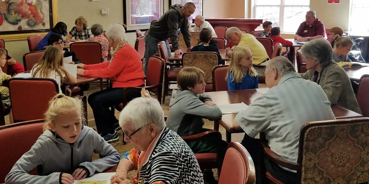 Seniors talking and spending time with young children in a dining room.