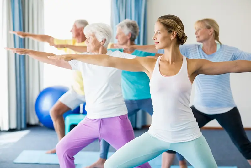 Seniors participating in a yoga class, while stretching.