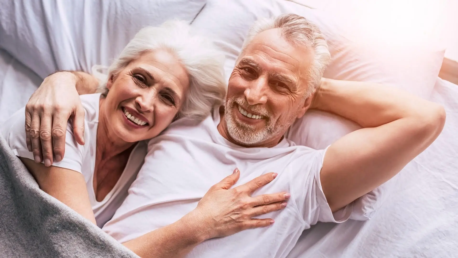 smiling elderly couple laying on the bed