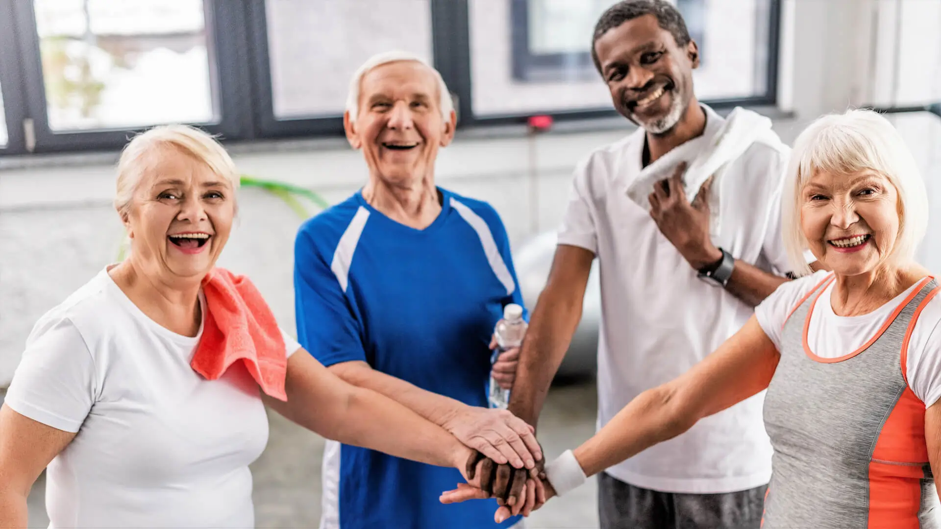 laughing senior multiculutral sportspeople putting hands together at gym