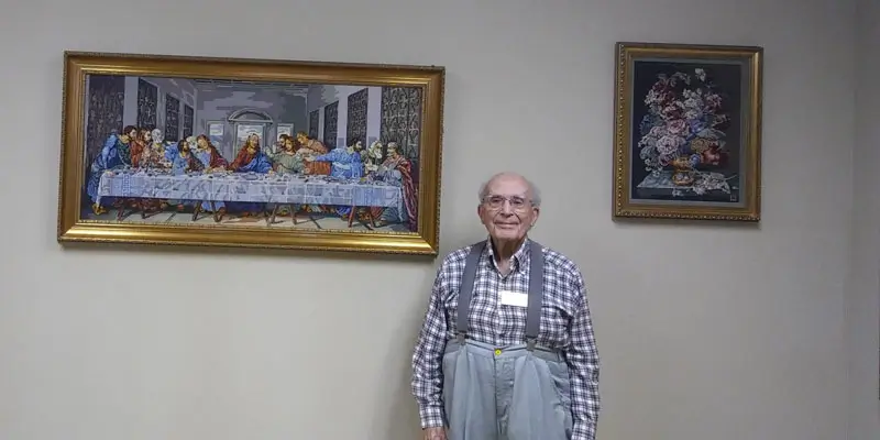 Al, with two of his needlepoint works, on display in the Bank Room. 