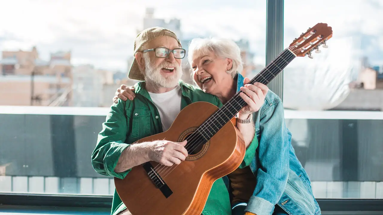 senior couple laughing while playing guitar