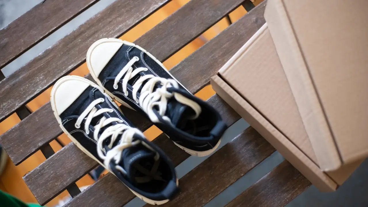 black sneakers on bench next to two cardboard boxes