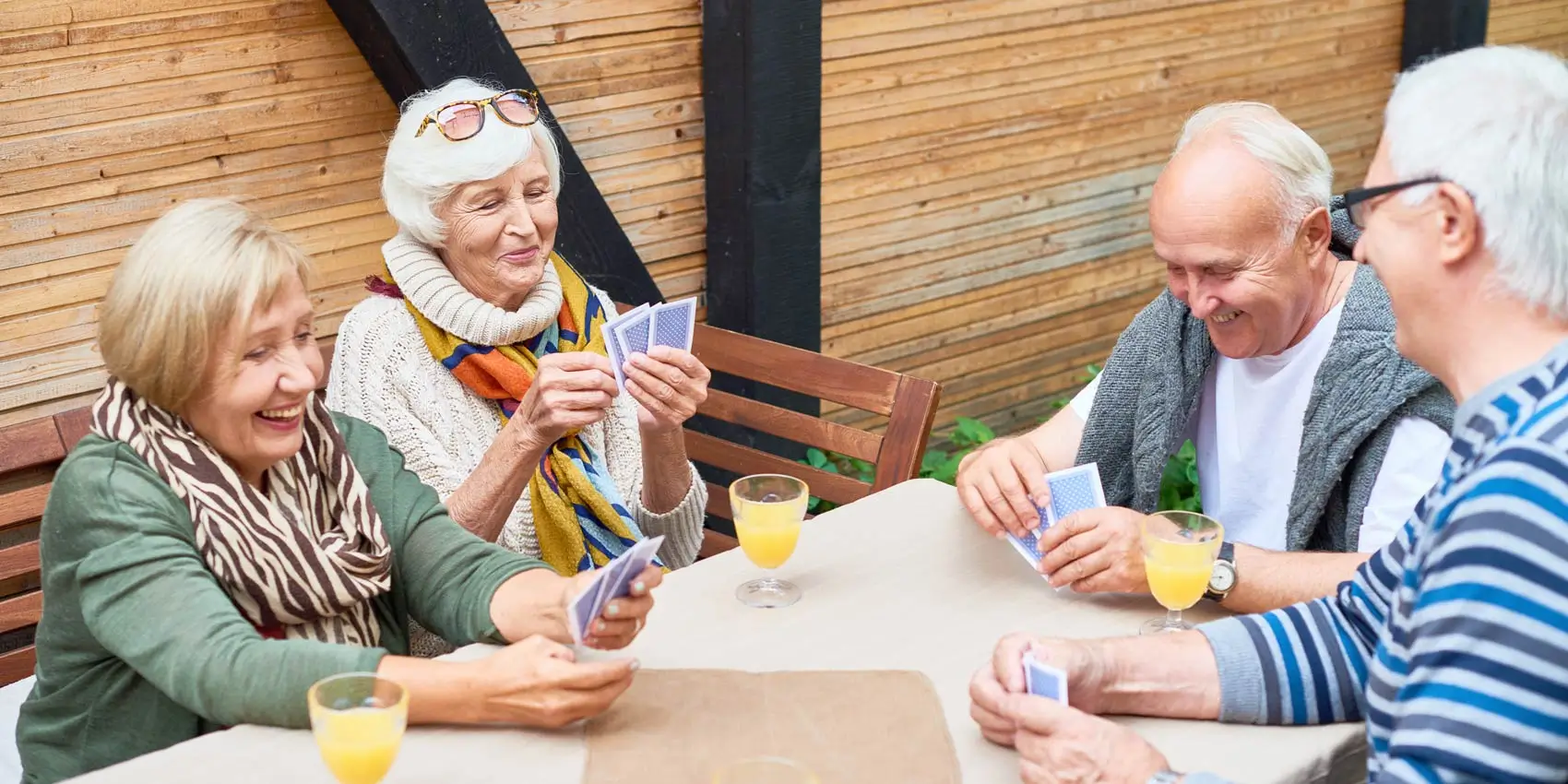 Senior friends playing cards outside.
