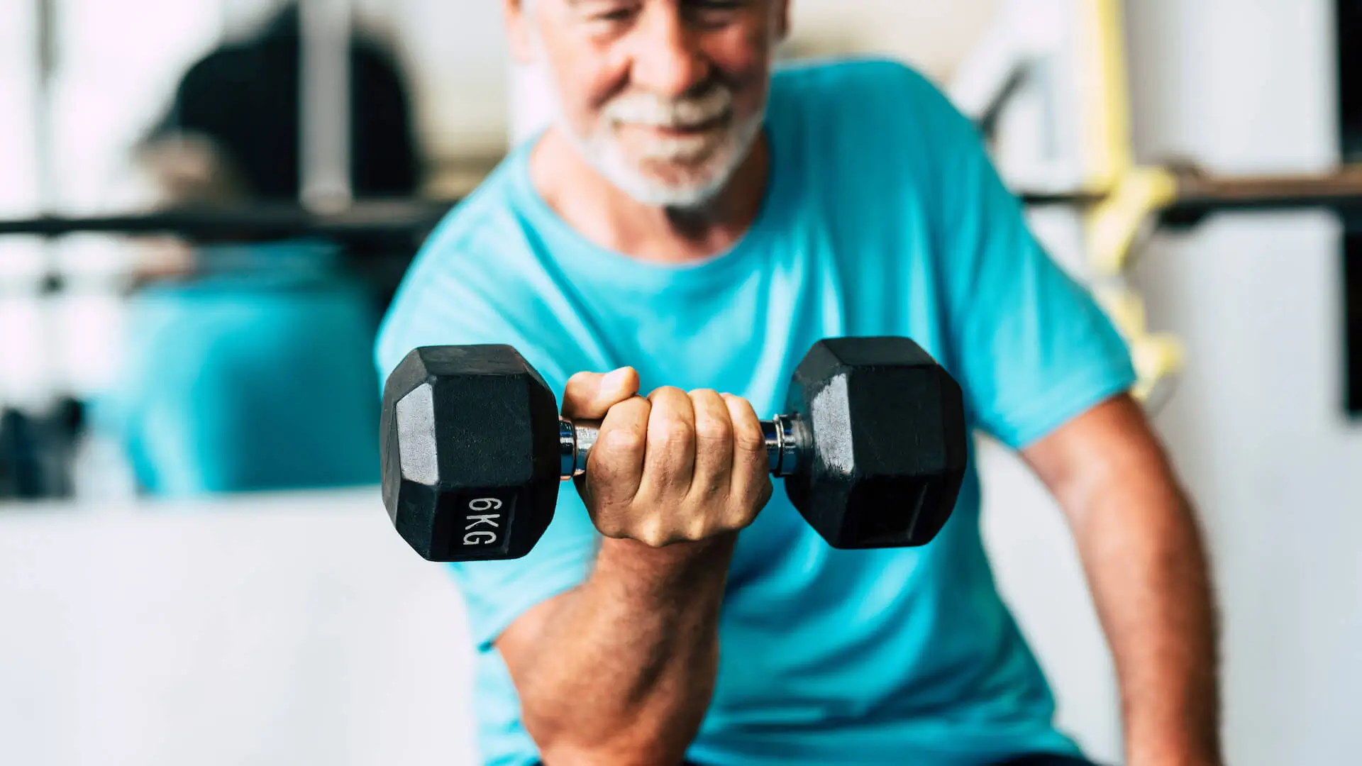 adult man and mature senior at the gym working his body with dumbbell - one man hapy training indoors sitted on the bench