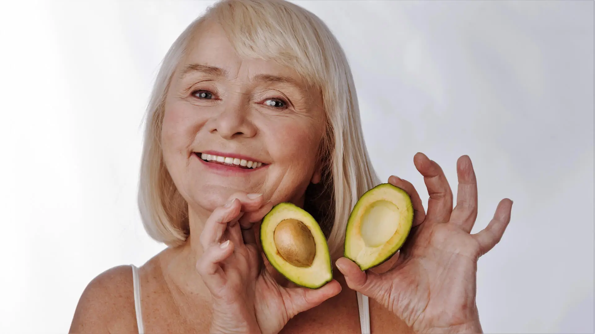 Cheerful happy woman showing you avocado halves