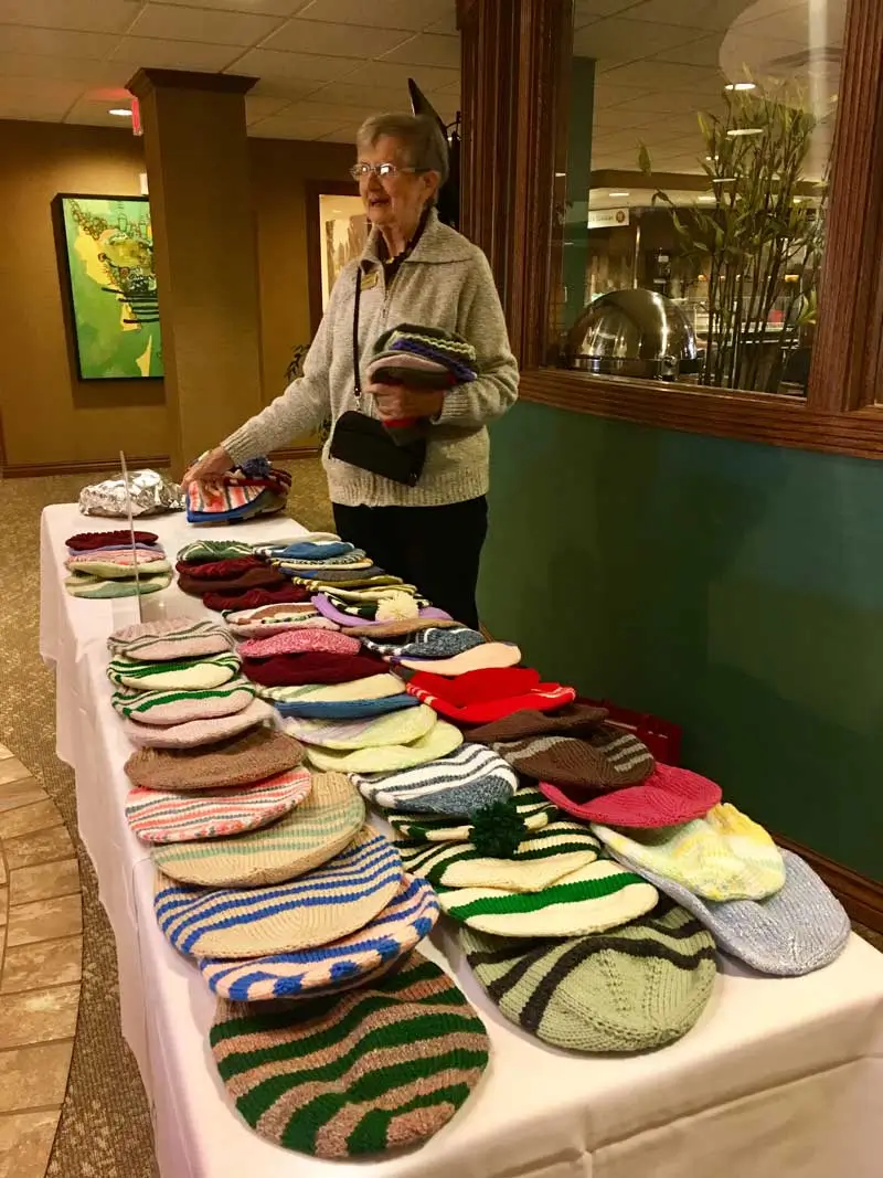 Senior giving away her quilted hats to people in need of them.