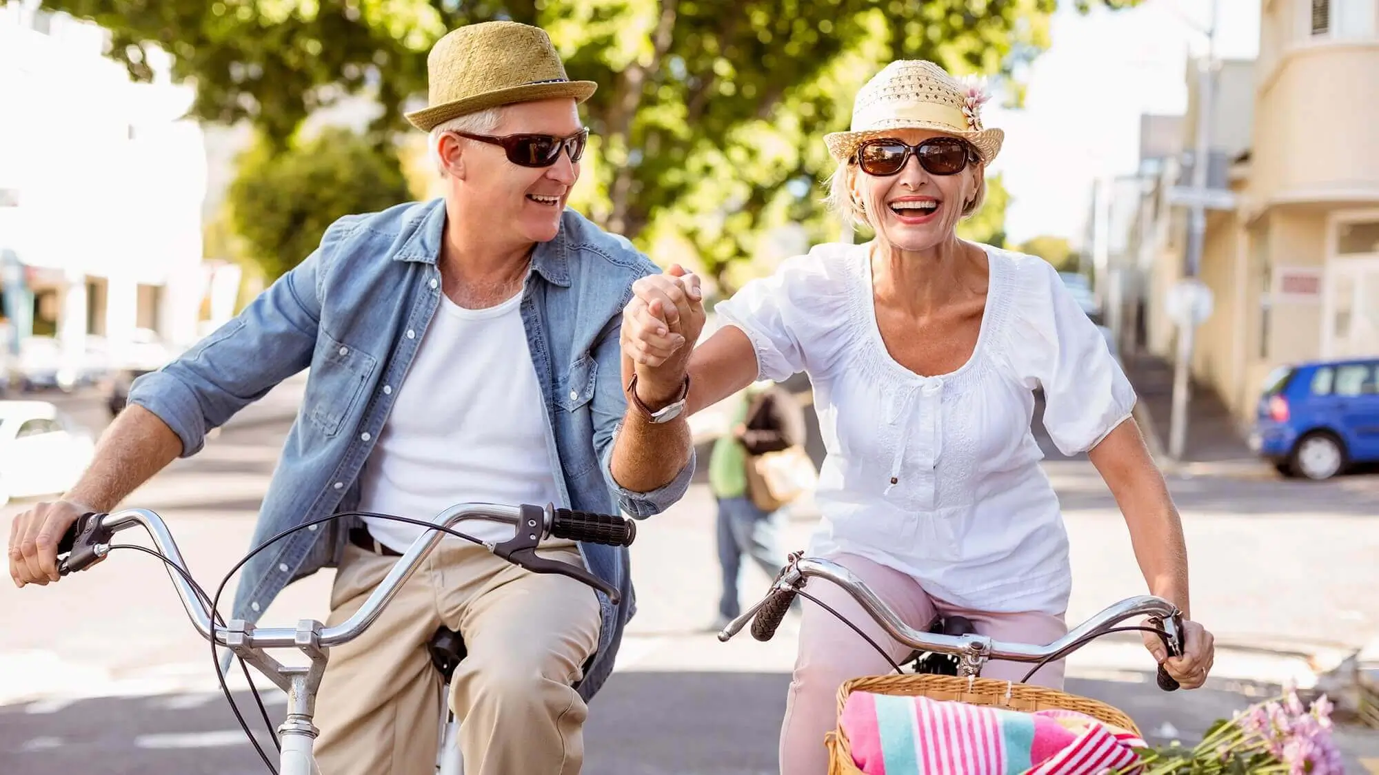 Elder couple holding hands riding bikes