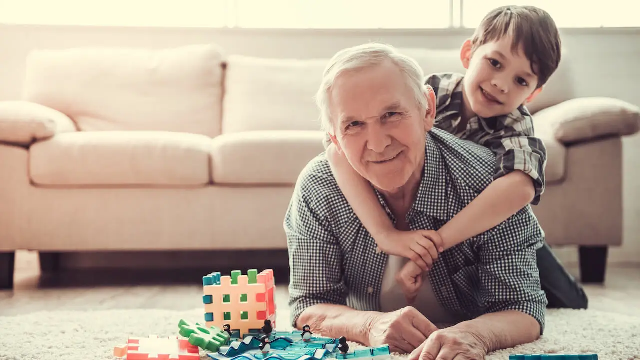 Grandpa playing toys with grandson hugging neck