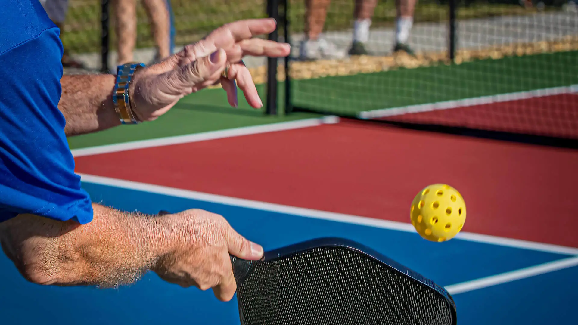 Over the shoulder shot of man hitting a pickleball with a paddle